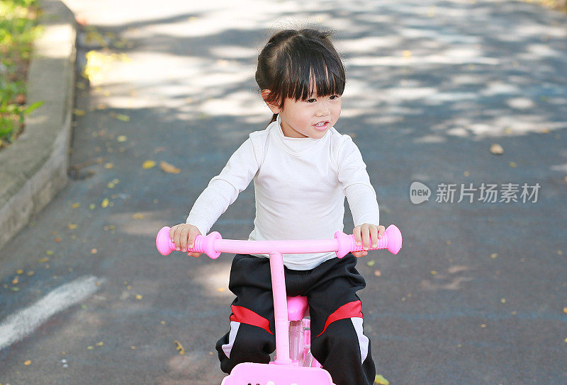 一个亚洲小女孩在公园里骑自行车。