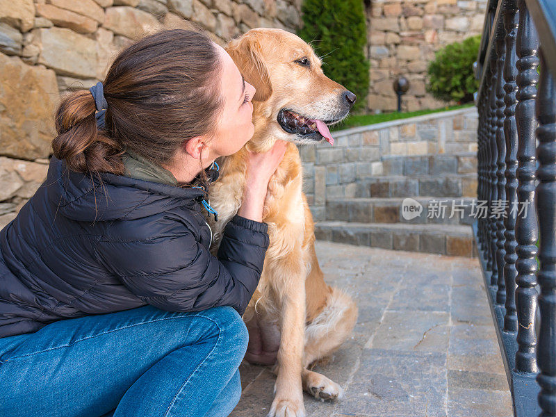 女孩坐在石阶上亲吻她的金毛猎犬