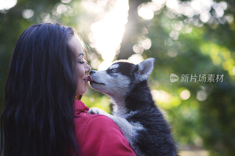 一个年轻女人带着狗在秋天的大自然中散步