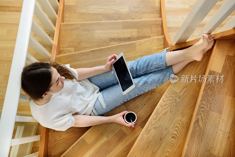 坐在楼梯上学习的女人。与咖啡