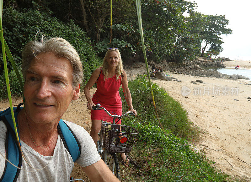 一对情侣在海滩上，丛林里骑自行车