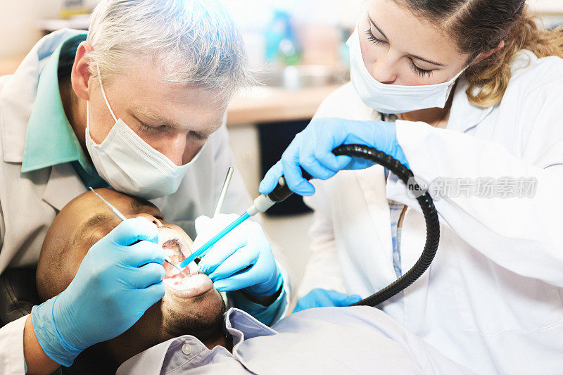 牙医和他的女助手在治疗男人的牙齿