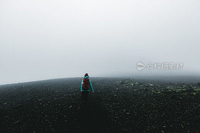 女人背包徒步旅行，虽然火山景观和风在冰岛无处