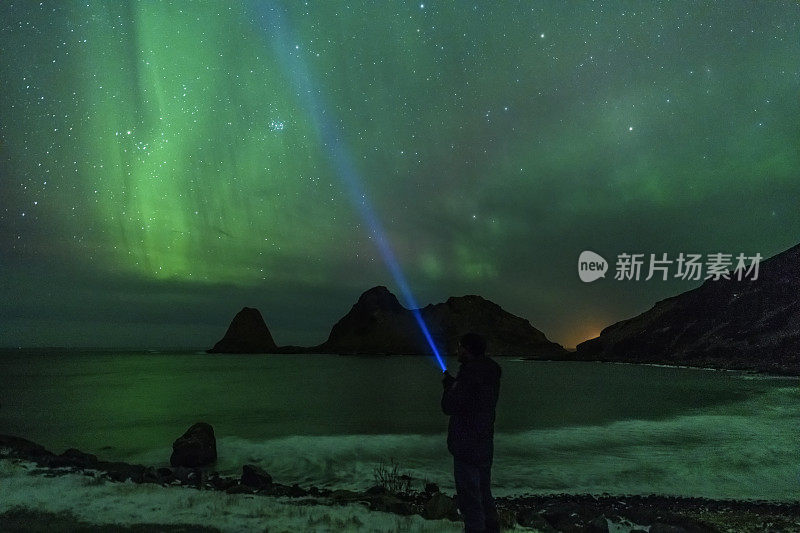 一个人拿着手电筒看北极光，罗浮敦上空的北极光