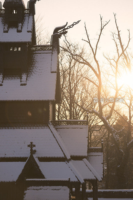 背光的木板教堂，在冬天屋顶上有雪