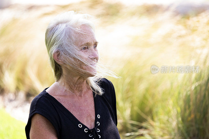 成熟女人的肖像在风天，背景与复制空间