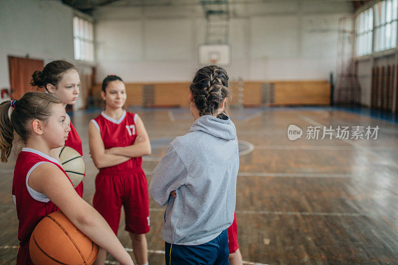 年轻女孩和她们的女子篮球教练在室内训练