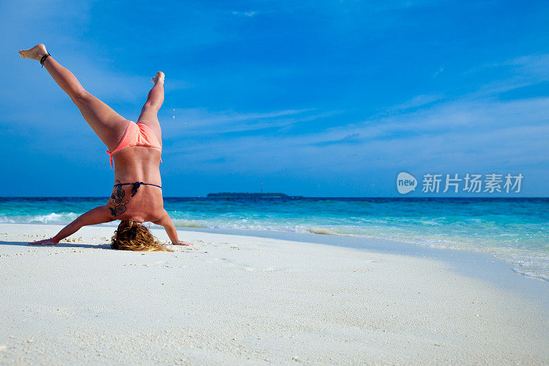 一名年轻女子在热带海滩上练习瑜伽
