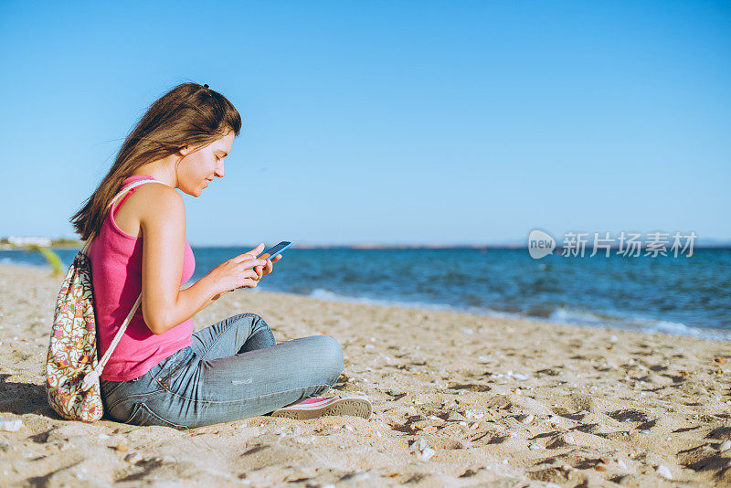 一个年轻女子在海滩上用手机