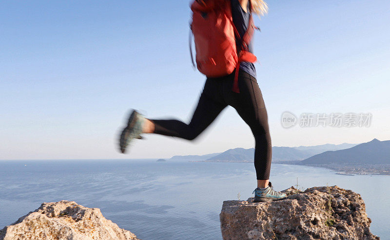 女性徒步旅行者在岩石峰顶之间跳跃