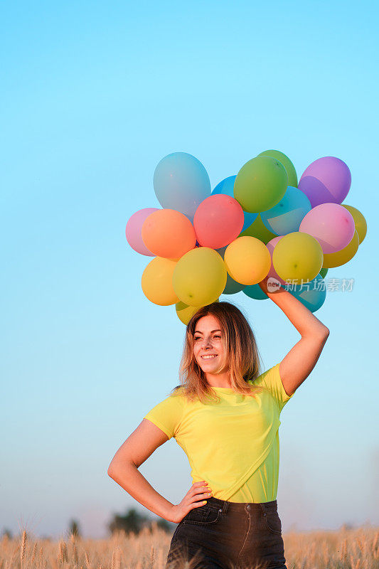 年轻女孩拿着一大束彩色气球