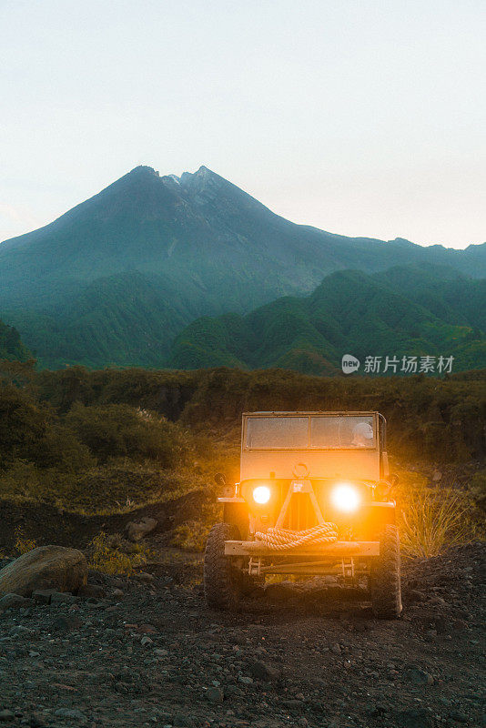 在默拉皮火山的背景上老式SUV的风景