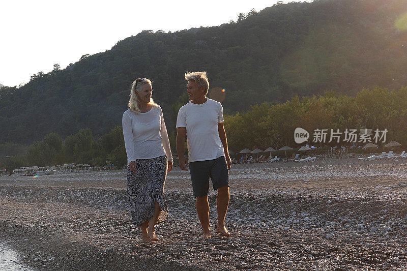 日出时，一对成熟的夫妇在海滩上散步