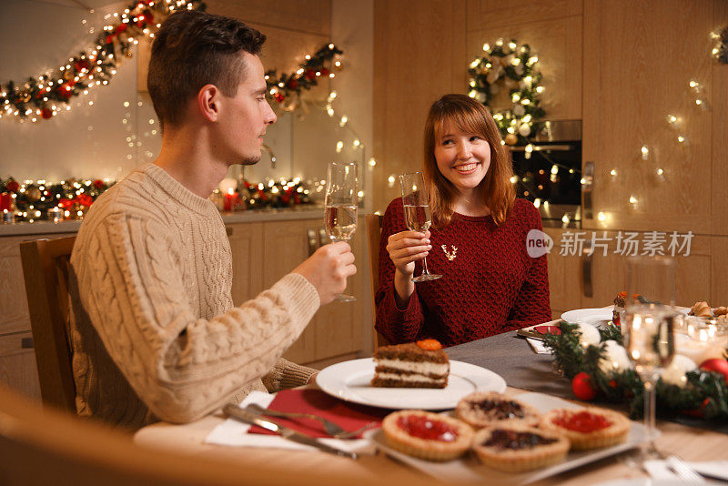 一对年轻夫妇在温馨的家里庆祝圣诞节。他们在平安夜喝香槟。