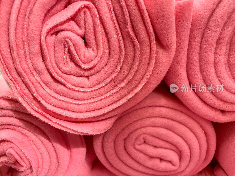 许多人把粉红色的彩色羊毛毯子卷起来放在商店里，家居舒适的概念
