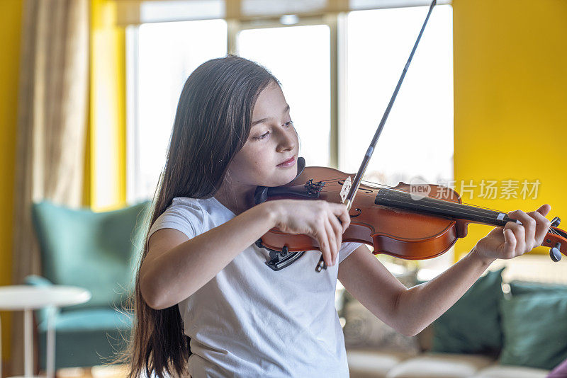 可爱的小女孩在家里拉小提琴