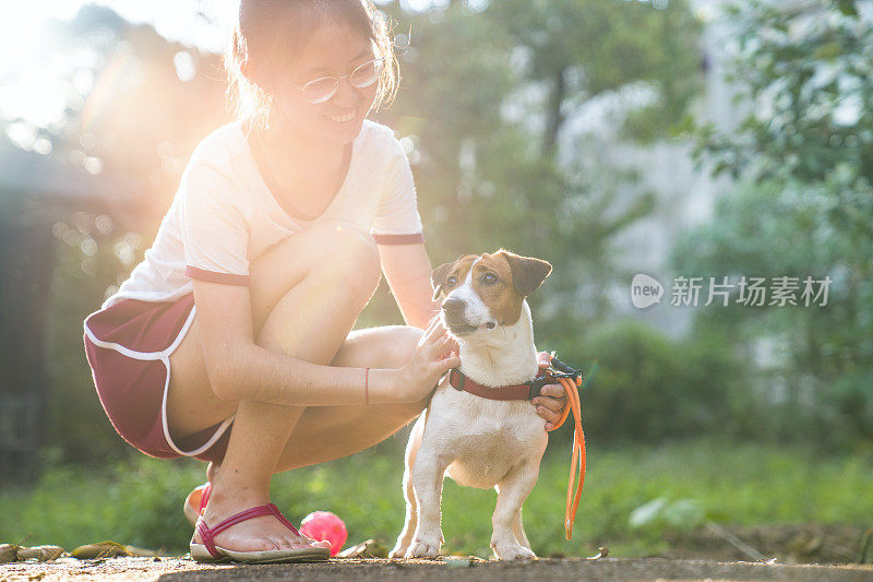 一个年轻的亚洲女孩和她可爱的宠物杰克罗素狗在夏天的公园里