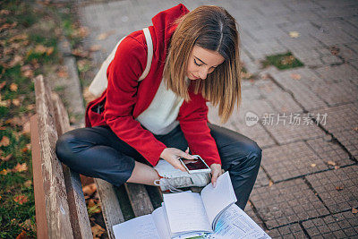 女学生坐在长凳上看书和学习