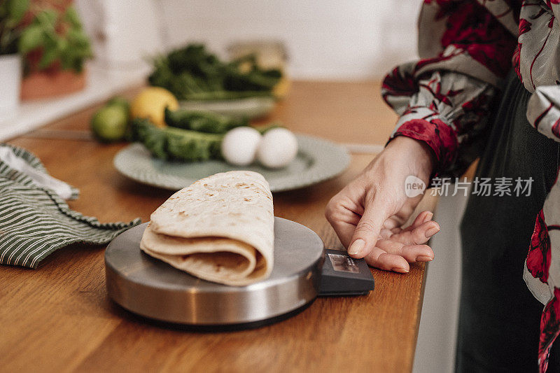 妇女称重她的食物计算热量饮食