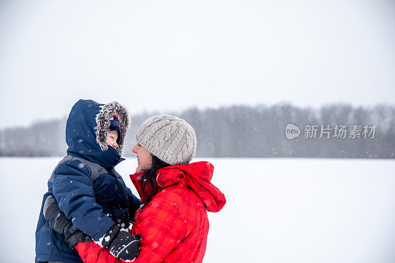 母亲和儿子在暴风雪期间户外玩耍