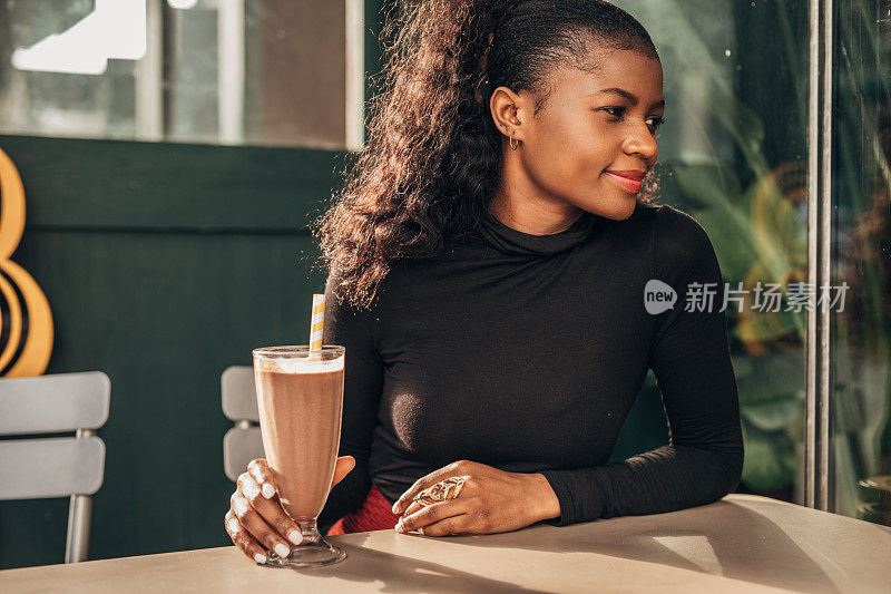 一个黑人女人独自坐在路边咖啡馆里