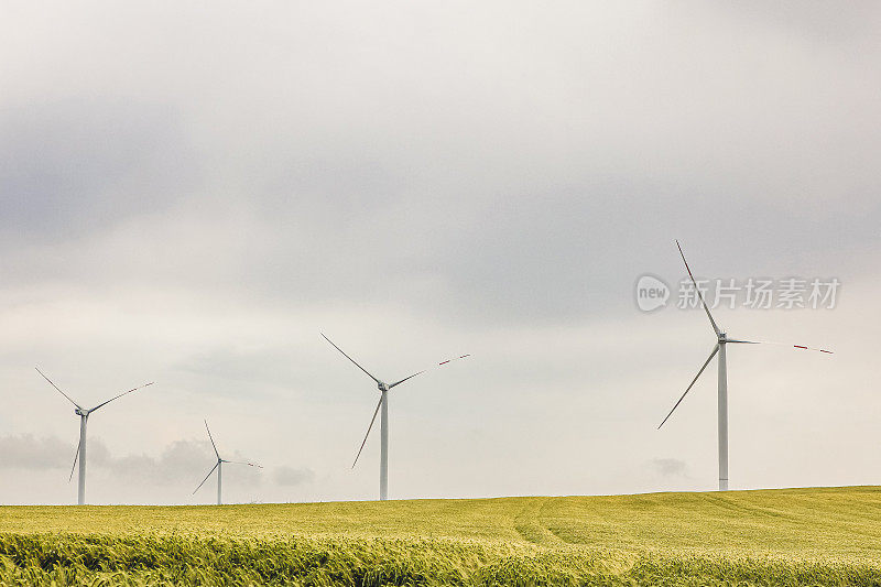 一组组的风车在黄土地上为发电生产小麦
