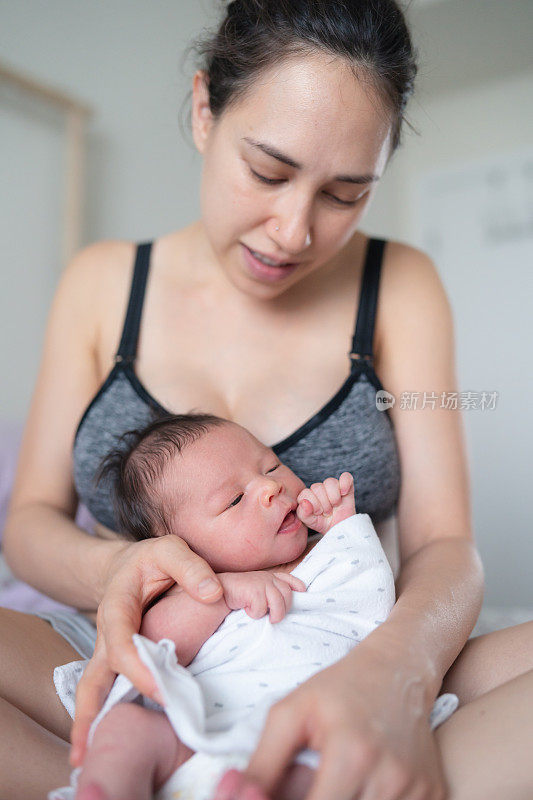 美丽的混血年轻母亲抱着新生的女儿