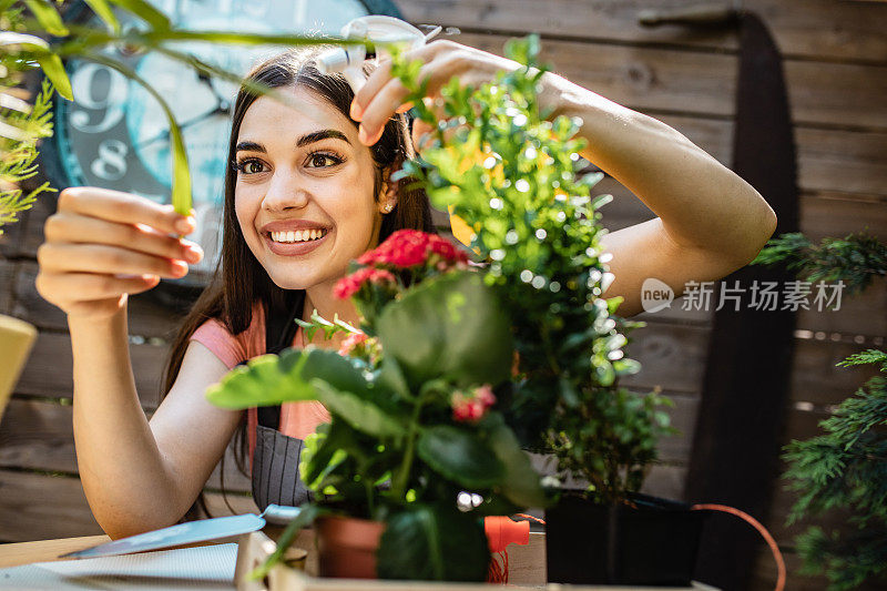 年轻女子的近距离照顾植物在她的后院