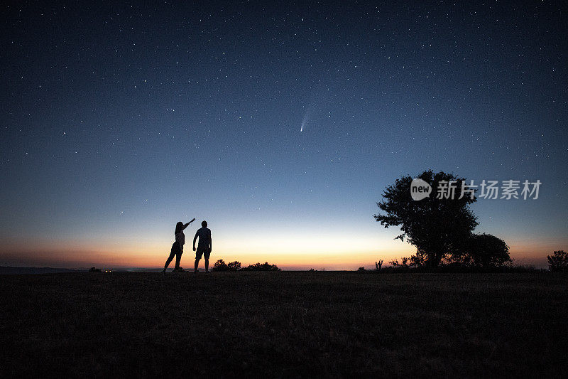 一对年轻的夫妇在明亮的夜空下看着Neowise彗星