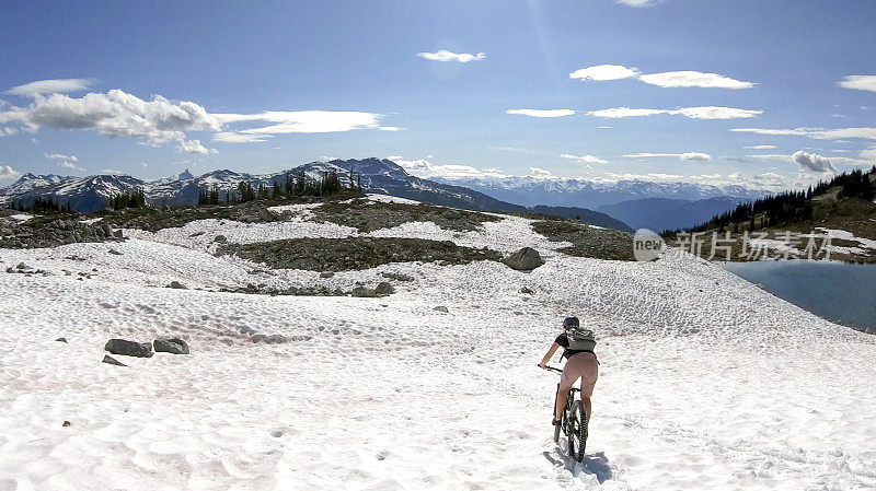 一名年轻女子骑着山地电动自行车滑下雪坡