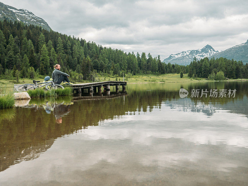 骑山地车的人在湖边看美丽的山景