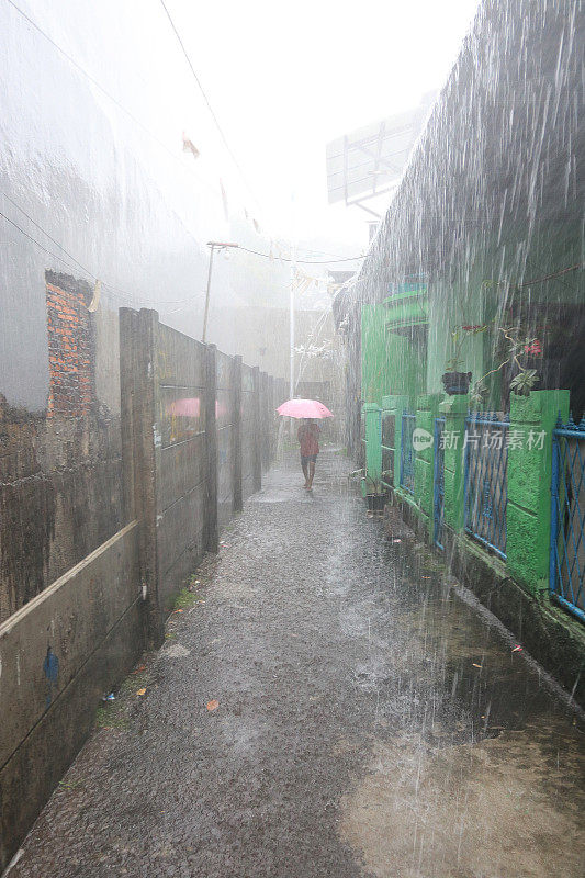 一个小女孩在倾盆大雨中带着雨伞。