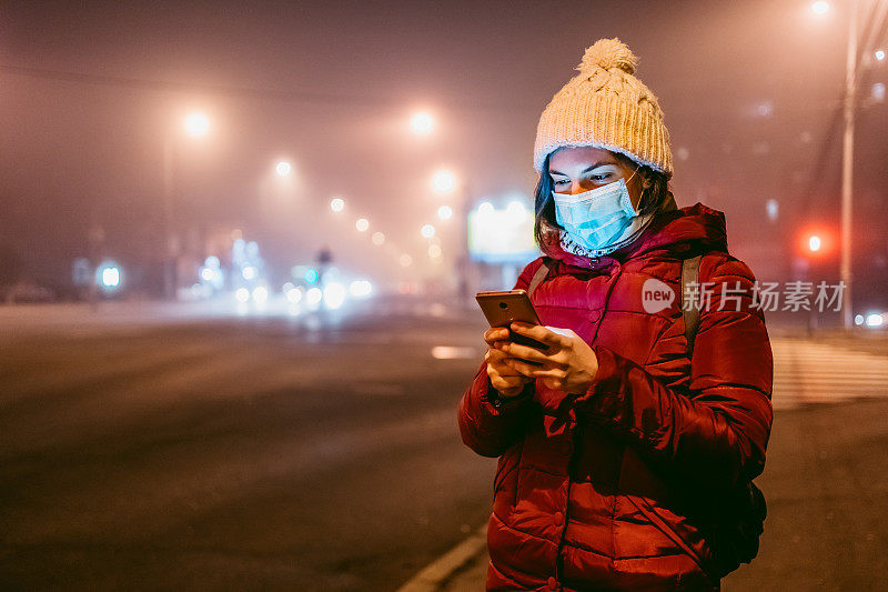 戴着口罩走在人行道上打电话的女人