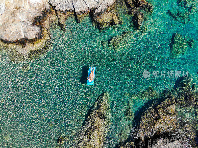 美丽的女人在海上的充气床垫上休息。