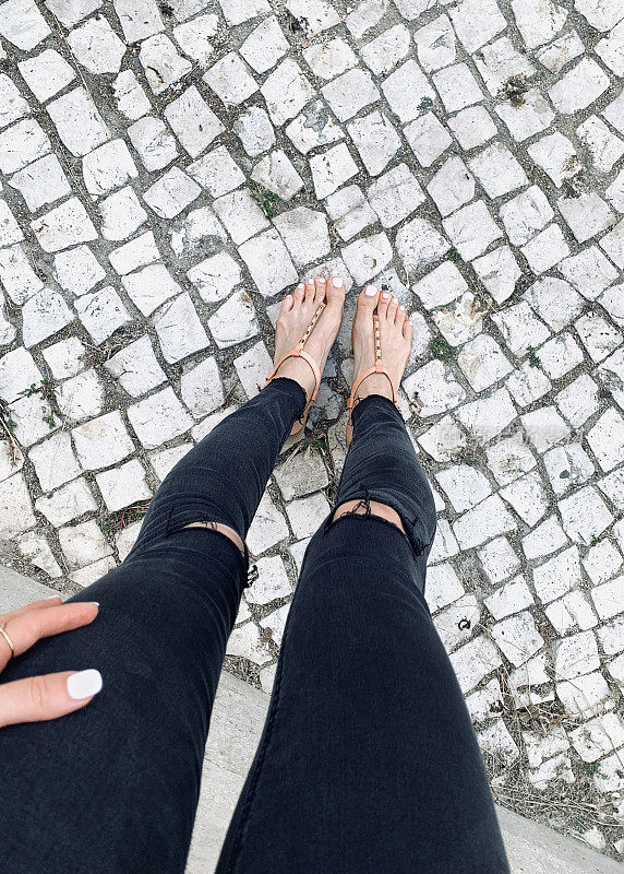 黑色破洞牛仔裤和葡萄牙式铺路石