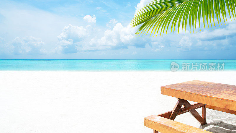 热带海滩上棕榈树下的木桌