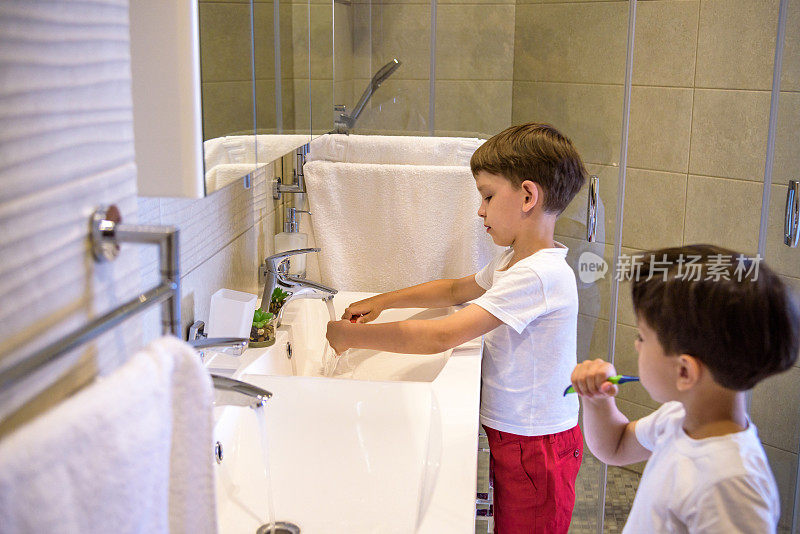 哥哥学着用镜子在浴室里给弟弟刷牙