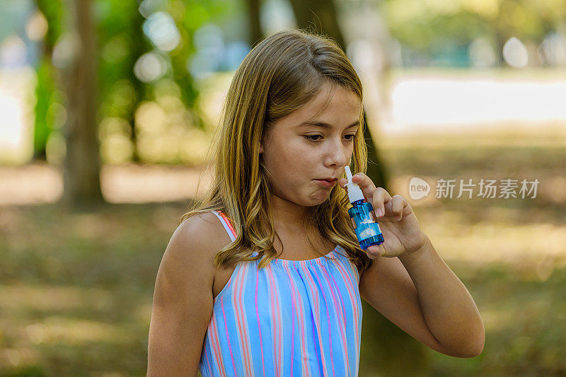 一个可爱的女孩在外面有过敏和使用鼻喷剂。