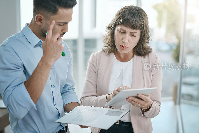 这是一个年轻的商人和女商人在现代办公室里一起使用数码平板电脑的照片