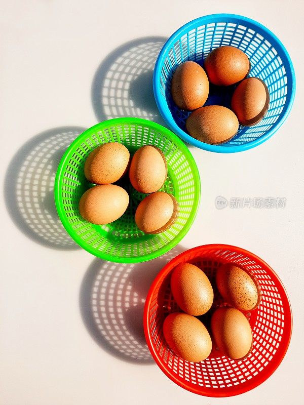 棕色鸡蛋在3个彩色篮子-白色背景。