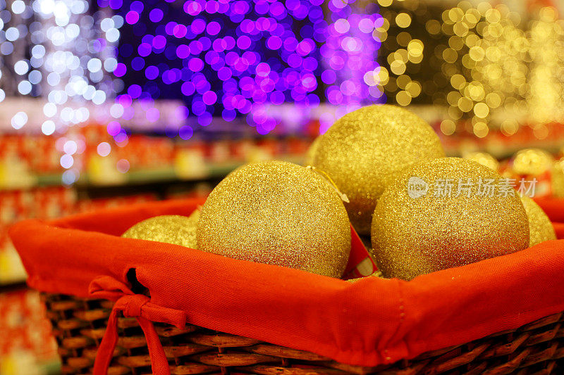 圣诞玩具，金色的球在红色的篮子上模糊的节日灯光背景