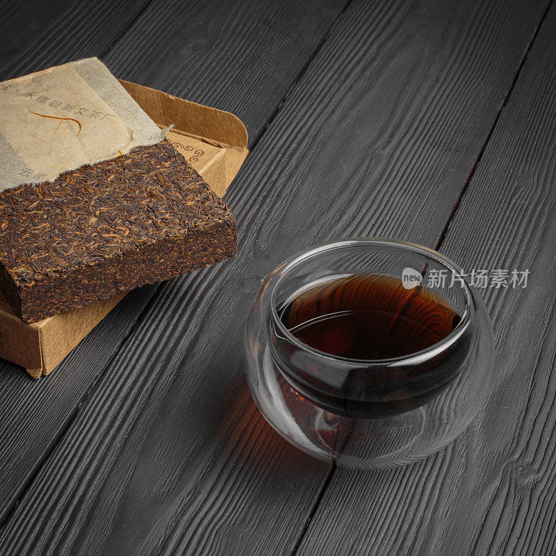 普洱茶在玻璃杯与普洱茶砖在深色木制背景