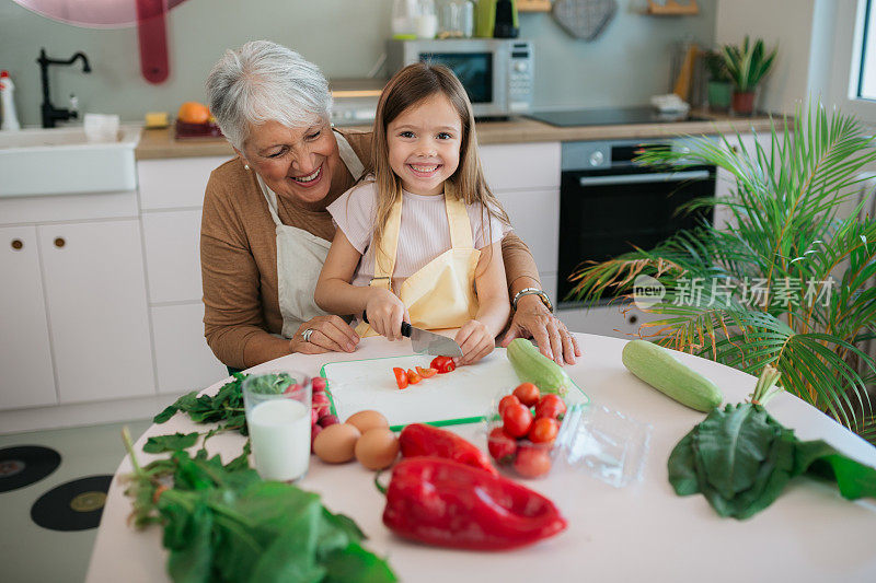 一位白人祖母教她的孙女如何准备食物的肖像