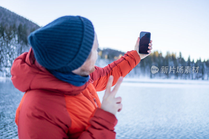 冬天，年轻人在湖边和森林边使用智能手机