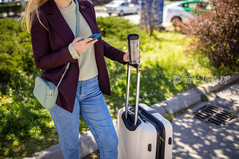 面目全非的年轻女子一边用手机，一边带着行李旅行