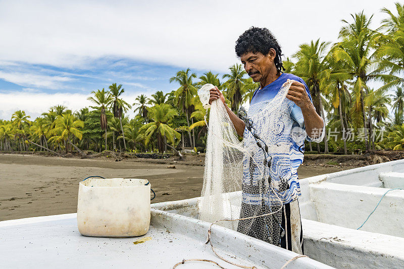 一个正在整理渔网的乡村渔民