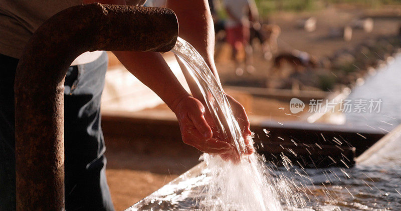 一名男子用从户外水管里流出的自来水洗手