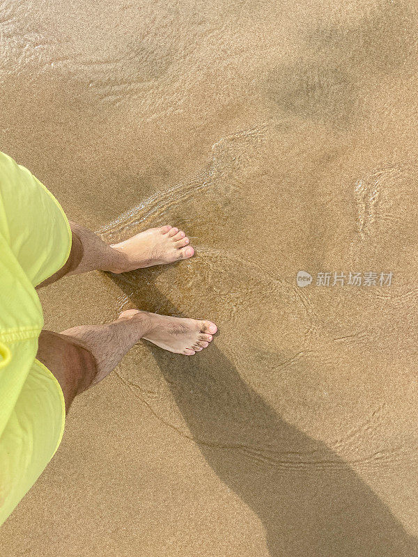 脚踩在沙滩上带着波浪