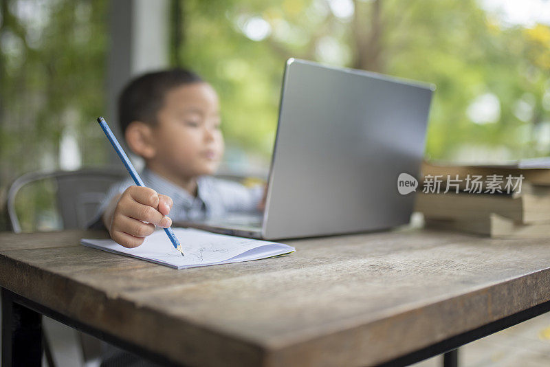 男孩正在学习用铅笔写字