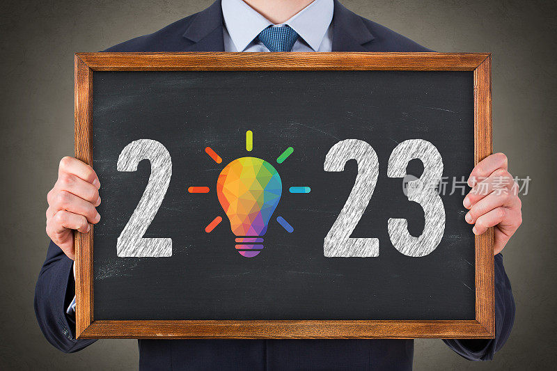 商人在黑板背景上画2023新年创意概念